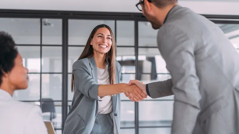 Business people handshaking across the table during a meeting in modern office.