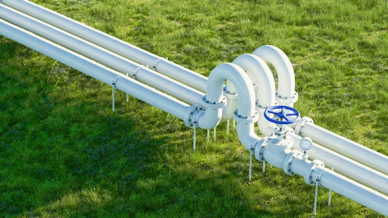 White gas and oil pipeline on lush grassy background.